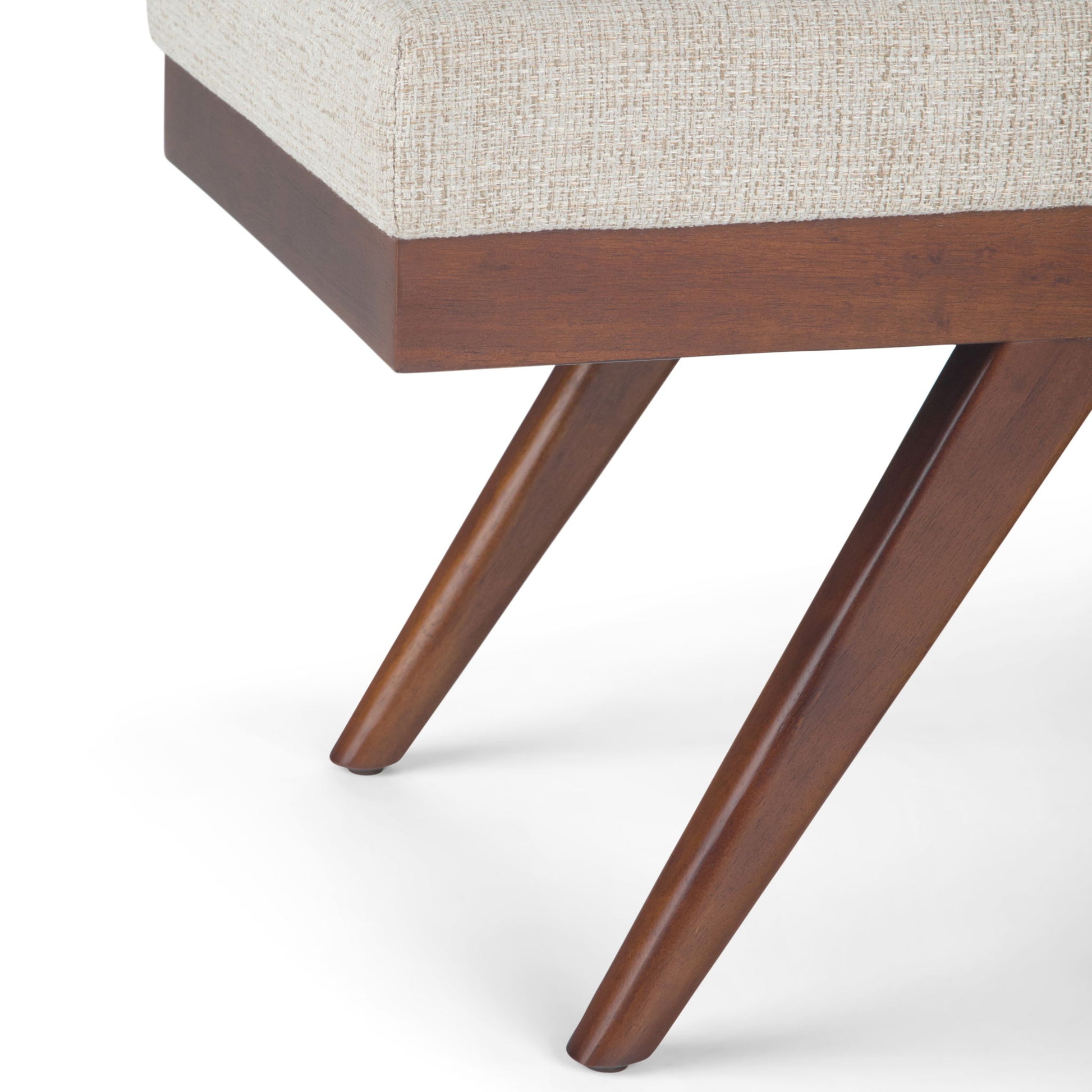 Close-up of the Chanelle - Mid-Century Ottoman Bench featuring angled wooden legs and a light beige upholstered seat, set against a white background.