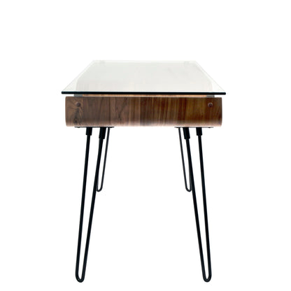 The Avery Mid-Century Modern Desk features a walnut wooden drawer, clear glass top, and black hairpin legs, shown from the front against a white background.