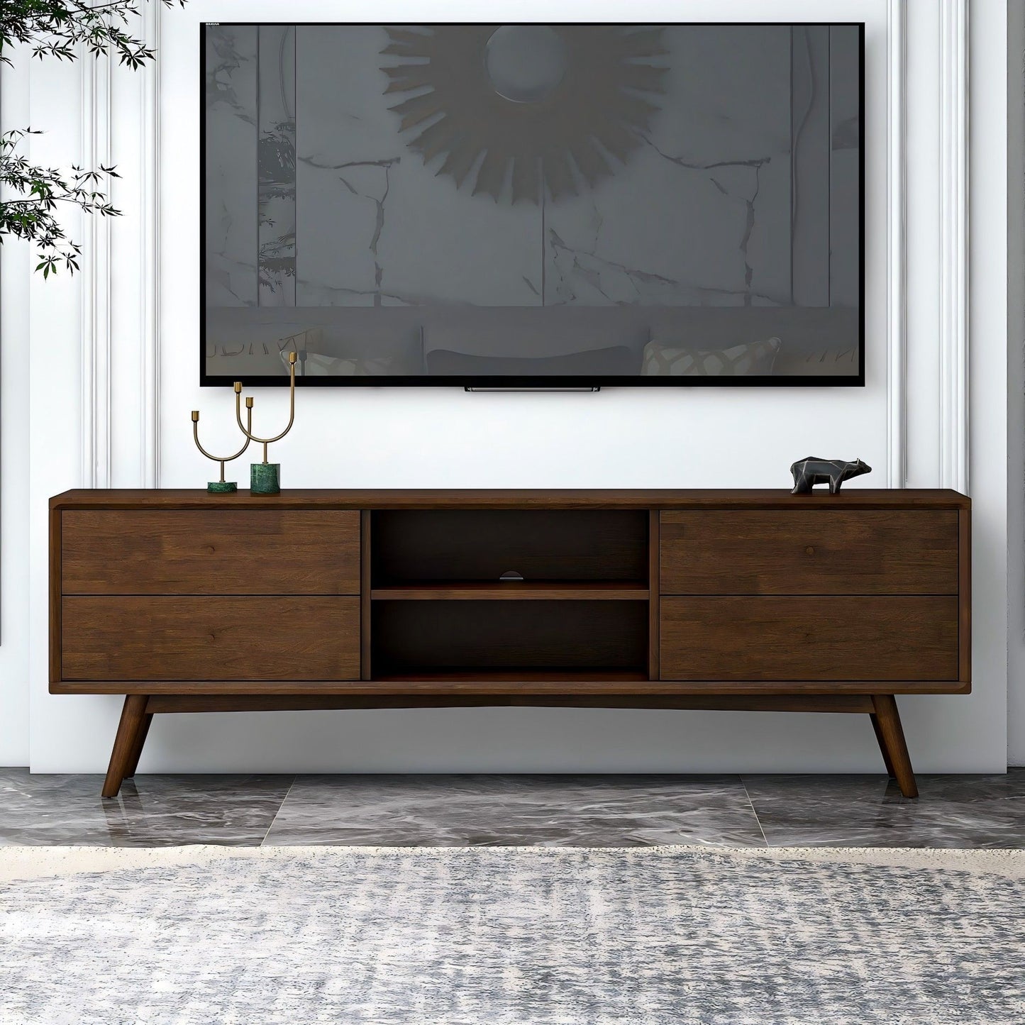A modern living room with a wall-mounted flat-screen TV above the Caroline - Modern TV Stand Up To 72", decorated with a gold candelabra and a small bear figurine.