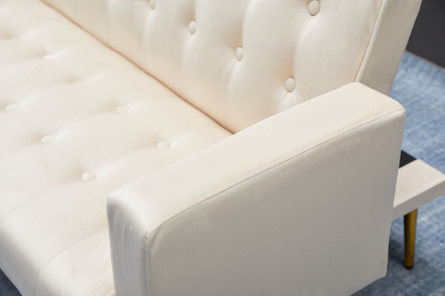 Close-up of the Comfort Compact Design Sofa Bed in light beige with tufted button details and a single armrest, placed on a blue textured rug.