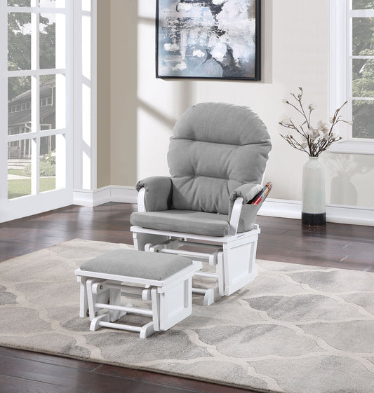 The Madison - Glider & Ottoman - White Base rests on a light-patterned rug in a bright, modern living room with large windows, hardwood floors, and a tall vase with branches.