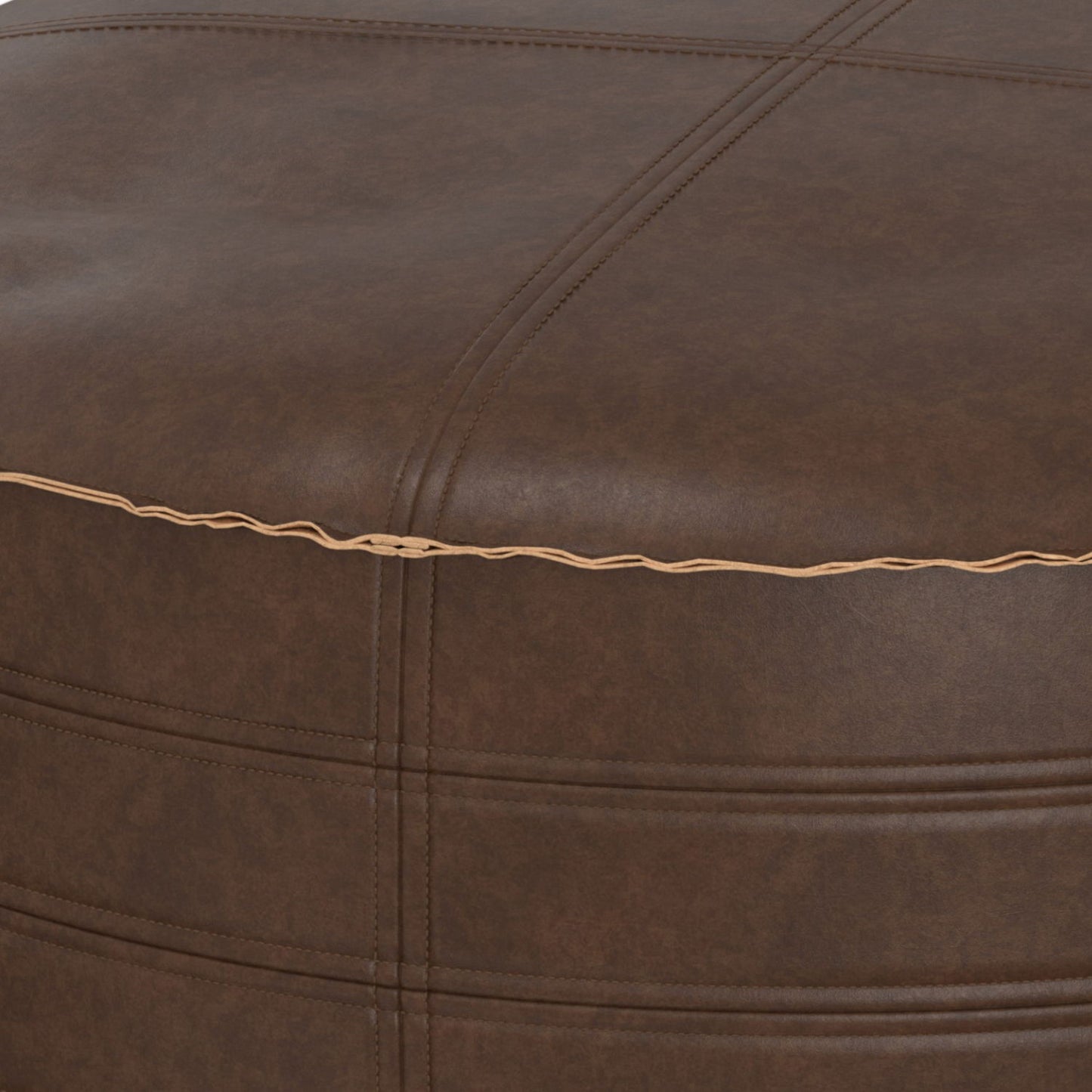 Close-up of the Brody - Round Pouf, featuring brown leather upholstery with visible stitching, a seam accented by tan thread, and a slightly textured surface.