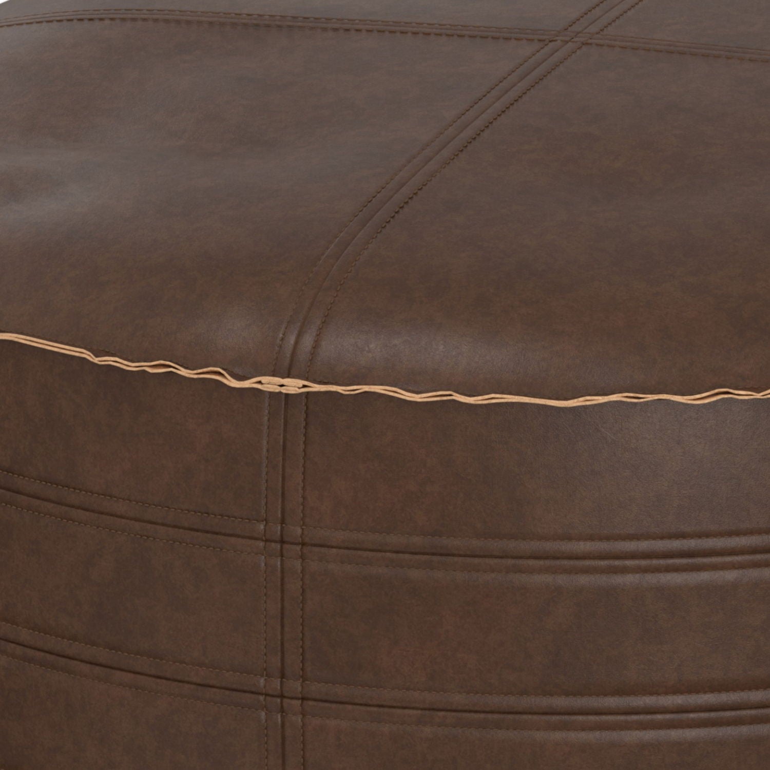 Close-up of the Brody - Round Pouf, featuring brown leather upholstery with visible stitching, a seam accented by tan thread, and a slightly textured surface.