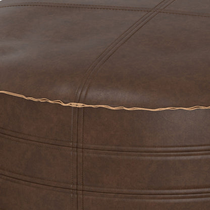 Close-up of the Brody - Round Pouf, featuring brown leather upholstery with visible stitching, a seam accented by tan thread, and a slightly textured surface.