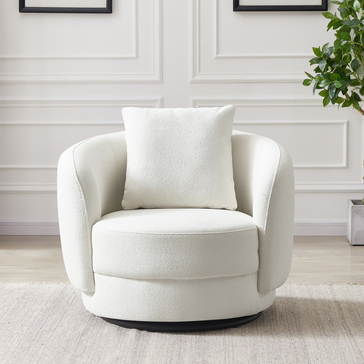 The Dylan Boucle Lounge Chair in modern white, featuring a matching square pillow, sits on a light rug beside a potted plant in a room with white paneled walls.