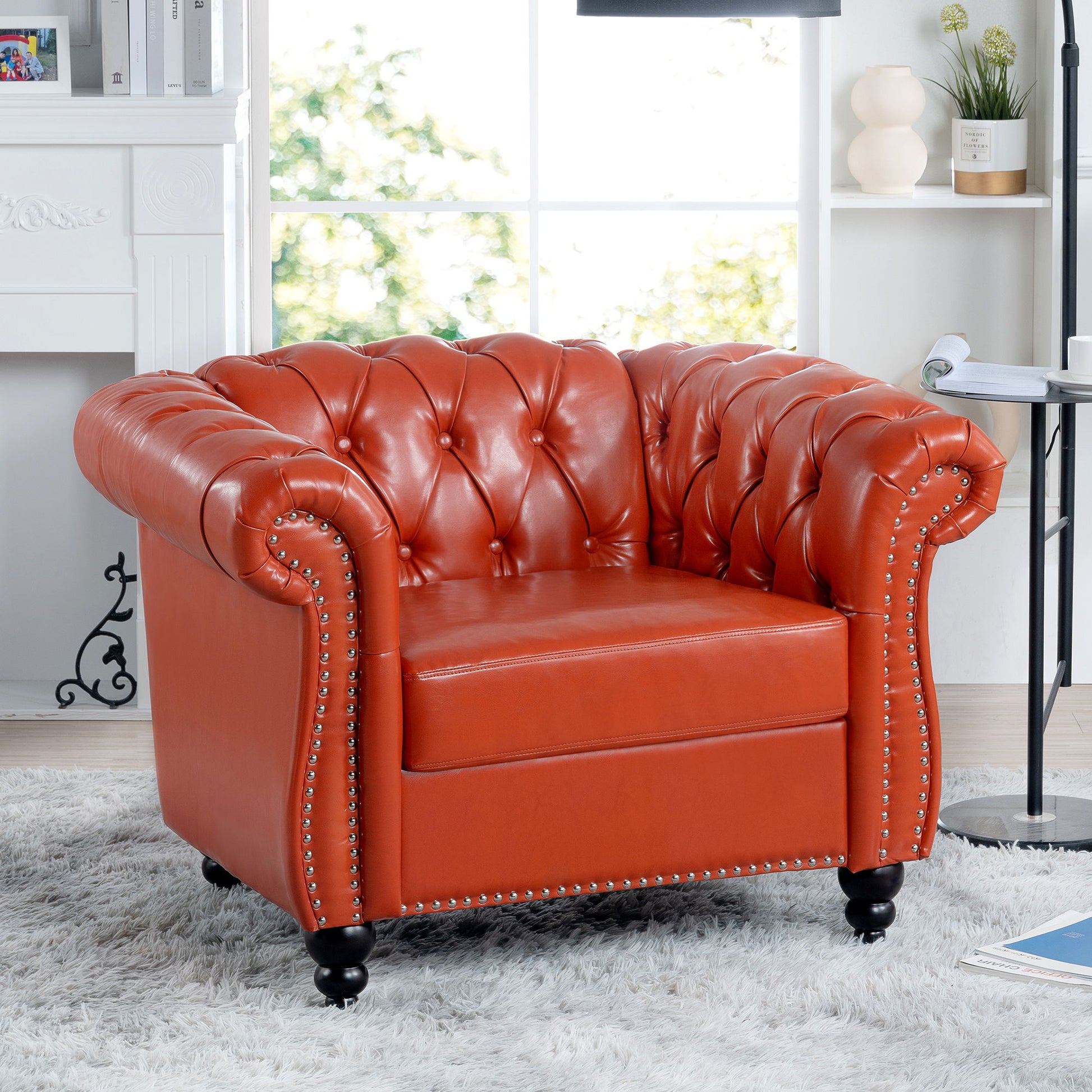 A 1 Seater Sofa For Living Room with red tufted leather, rolled arms, and nailhead trim sits on a light gray shag rug in a bright modern space with large windows and decorative shelves.