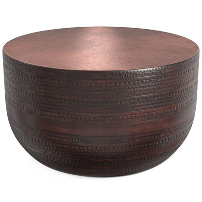 The Johnsen - Handcrafted Metal Coffee Table features a round, dark brown design with a flat top and engraved textured patterns around the sides.