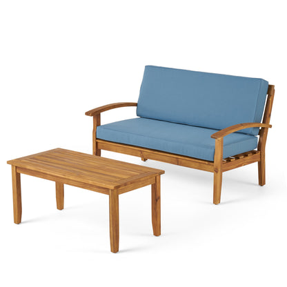 The Outdoor Chat Set With Coffee Table And Loveseat features a wooden loveseat with blue cushions and a matching rectangular coffee table, both displayed on a white background.