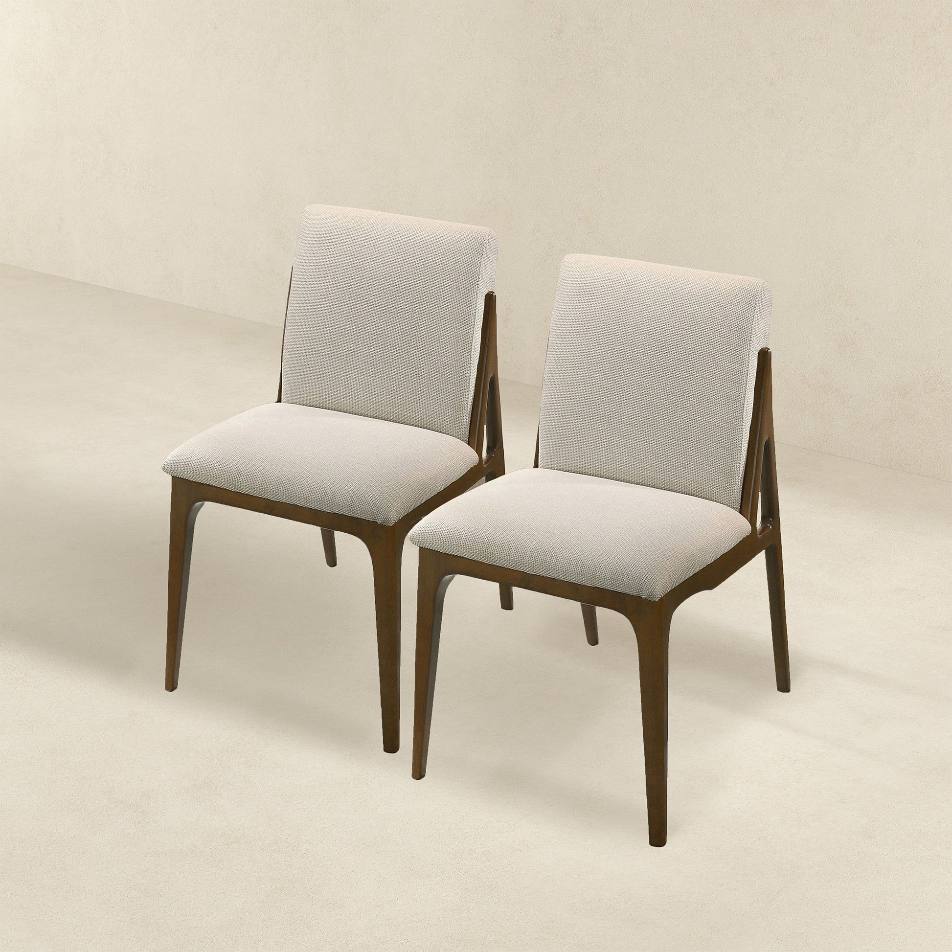 The Grivelle - Elegant Dining Chair (Set of 2) features modern design with light beige upholstered seats and backs, complemented by dark wooden frames and legs, shown side by side on a light floor against a neutral background.