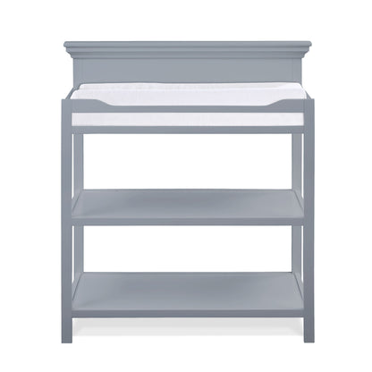 The Universal - Changing Table features a gray wooden design with a white changing pad on top and two open storage shelves, displayed against a plain white background.