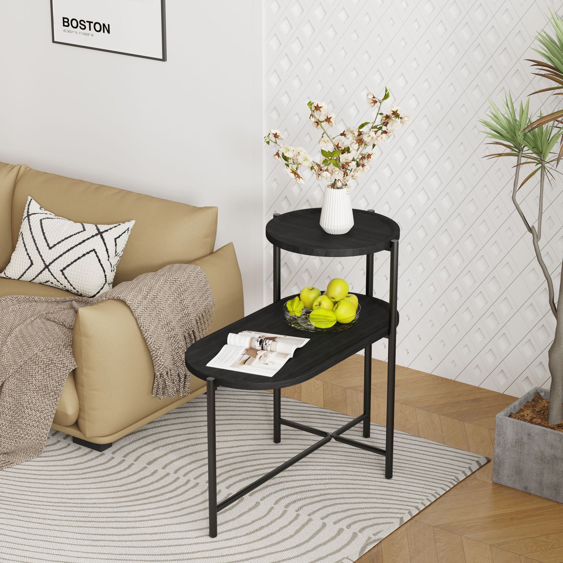 A modern living room features a tan sofa with a patterned cushion and beige throw, a Round Coffee Table With Storage Tray 2 Tier Oval End Tables holding apples, magazines, and flowers, a potted plant, and a white textured wall.