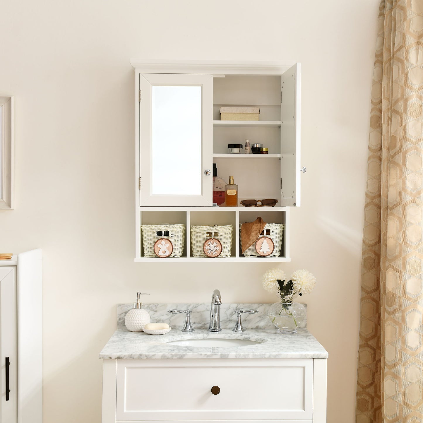 The white Bathroom Storage Cabinet features mirrored double doors, two adjustable shelves, and three Christmas-style storage baskets. It hangs above a marble sink with a silver faucet; decorative items and a vase of white flowers sit on the countertop.