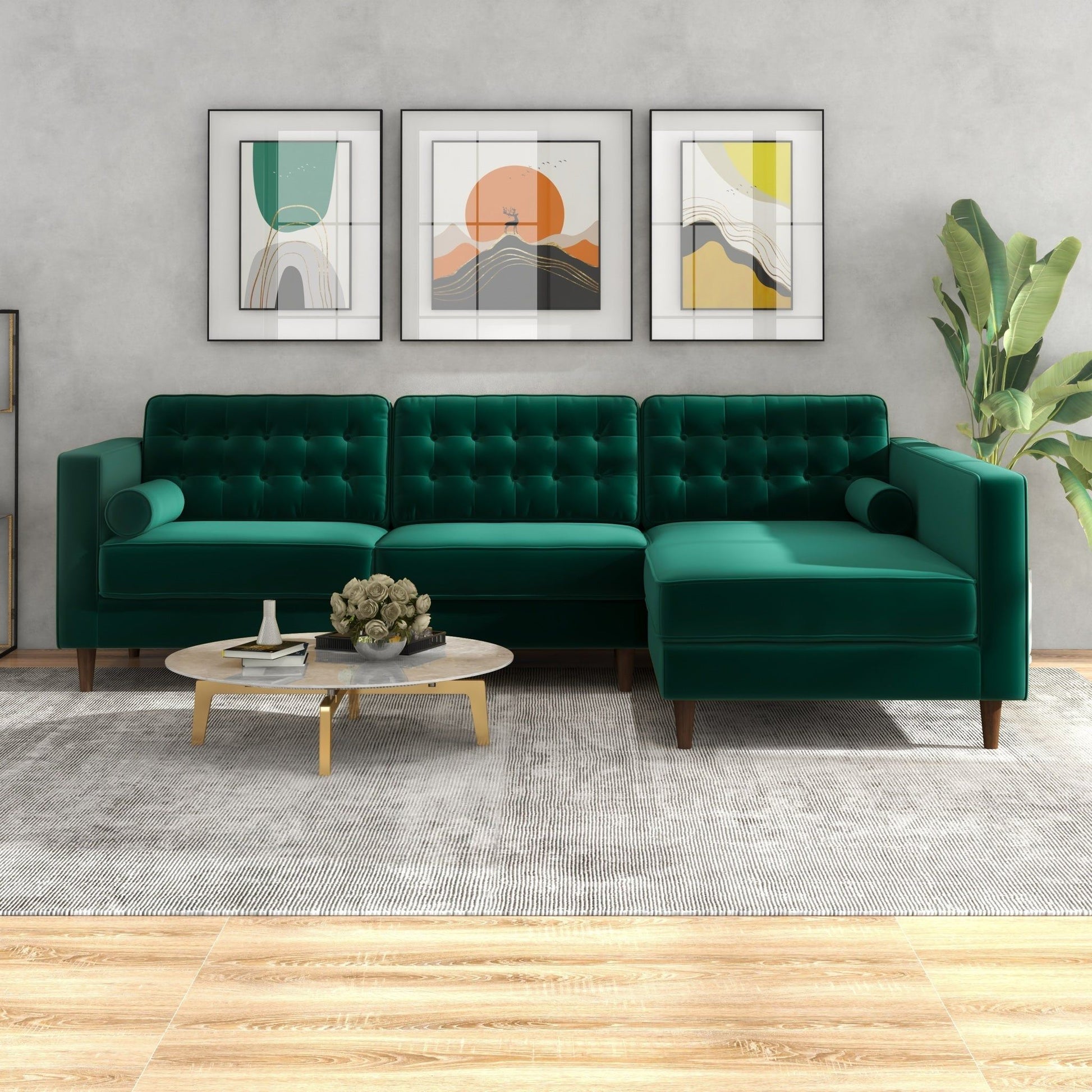 A modern living room featuring the Christian Mid-Century Modern Design Sectional Sofa in green velvet, a round coffee table with flowers, a large gray rug, three abstract art prints on the wall, and a tall plant in the corner.