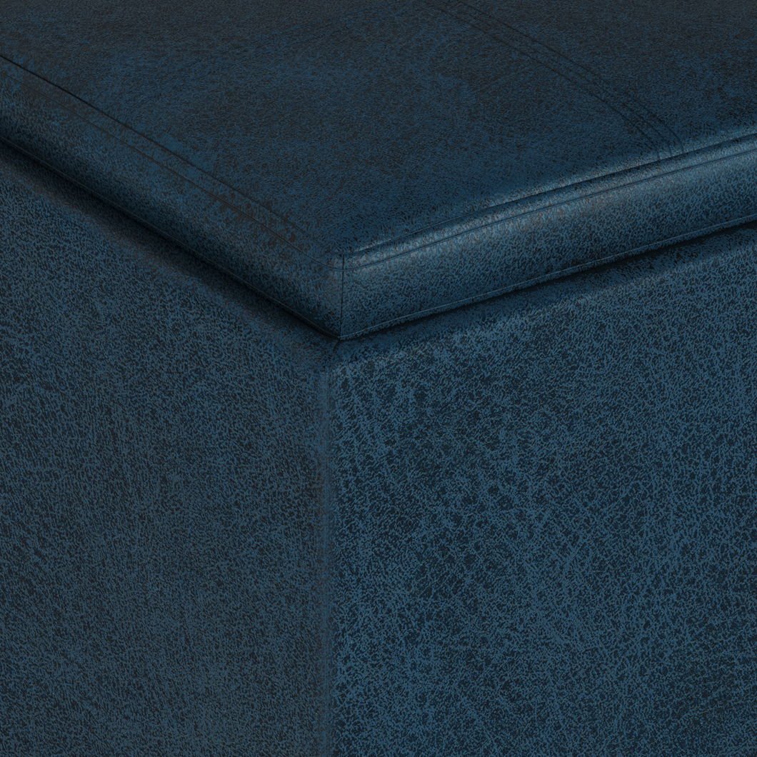 Close-up of the corner of the Rockwood Upholstered Cube Storage Ottoman With Tray in dark blue, highlighting its textured fabric and visible top-edge stitching.