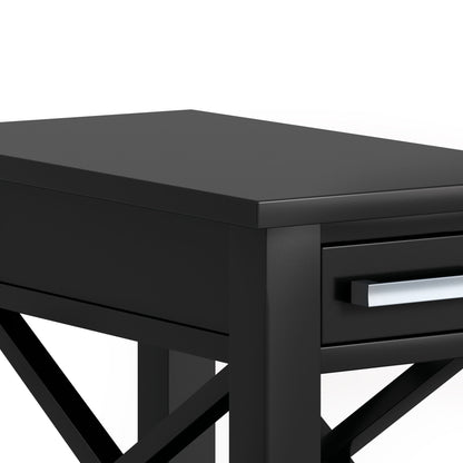 Close-up of the Kitchener - Handcrafted Table’s corner, showing its modern black wood finish, drawer with silver handle, and X-shaped side support, set against a white background.