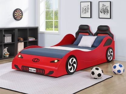 A children's bedroom featuring the Colen - Twin Car Bed With LED in red, pillows, a shelf with toys and books, wall art, a window showing greenery, and three sports balls on a white rug.