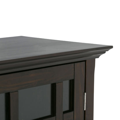 Close-up of the top corner of the Bedford - Storage Media Cabinet, featuring a dark wood finish, a glass panel door, and a visible metal hinge.
