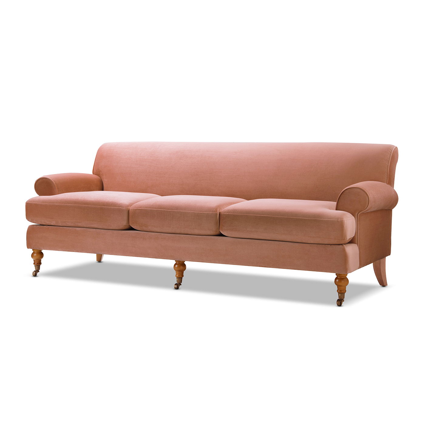 The Alana Lawson - Three Cushion Tightback Sofa is a pink velvet three-seater with rolled arms, three seat cushions, and four wooden legs—two are turned and fitted with casters.