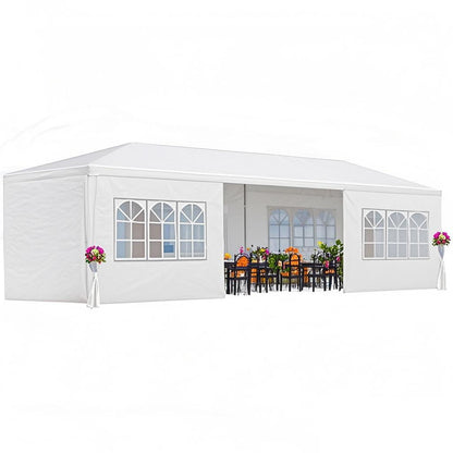A 10x20' Outdoor Garden Gazebo Wedding Party Tent Canopy Marquee with removable sidewalls, featuring elegant arched windows and decorated with flower arrangements at the corners, has a long table and chairs set up inside.