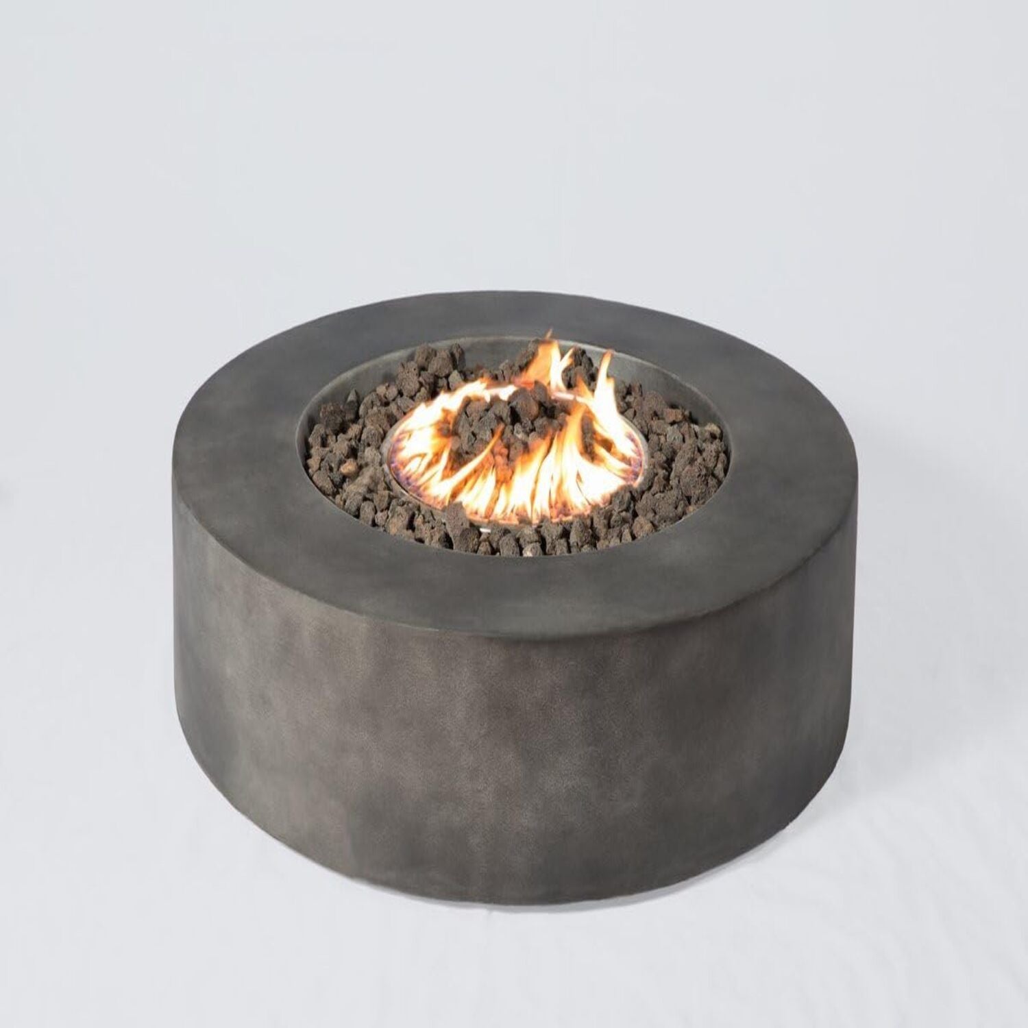 The Fibre Reinforced Outdoor Fire Pit Table - Charcoal features a round, modern design with a dark gray concrete finish, black lava rocks, and central flames, shown against a plain white background.