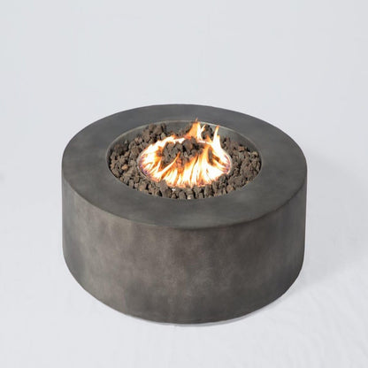 The Fibre Reinforced Outdoor Fire Pit Table - Charcoal features a round, modern design with a dark gray concrete finish, black lava rocks, and central flames, shown against a plain white background.