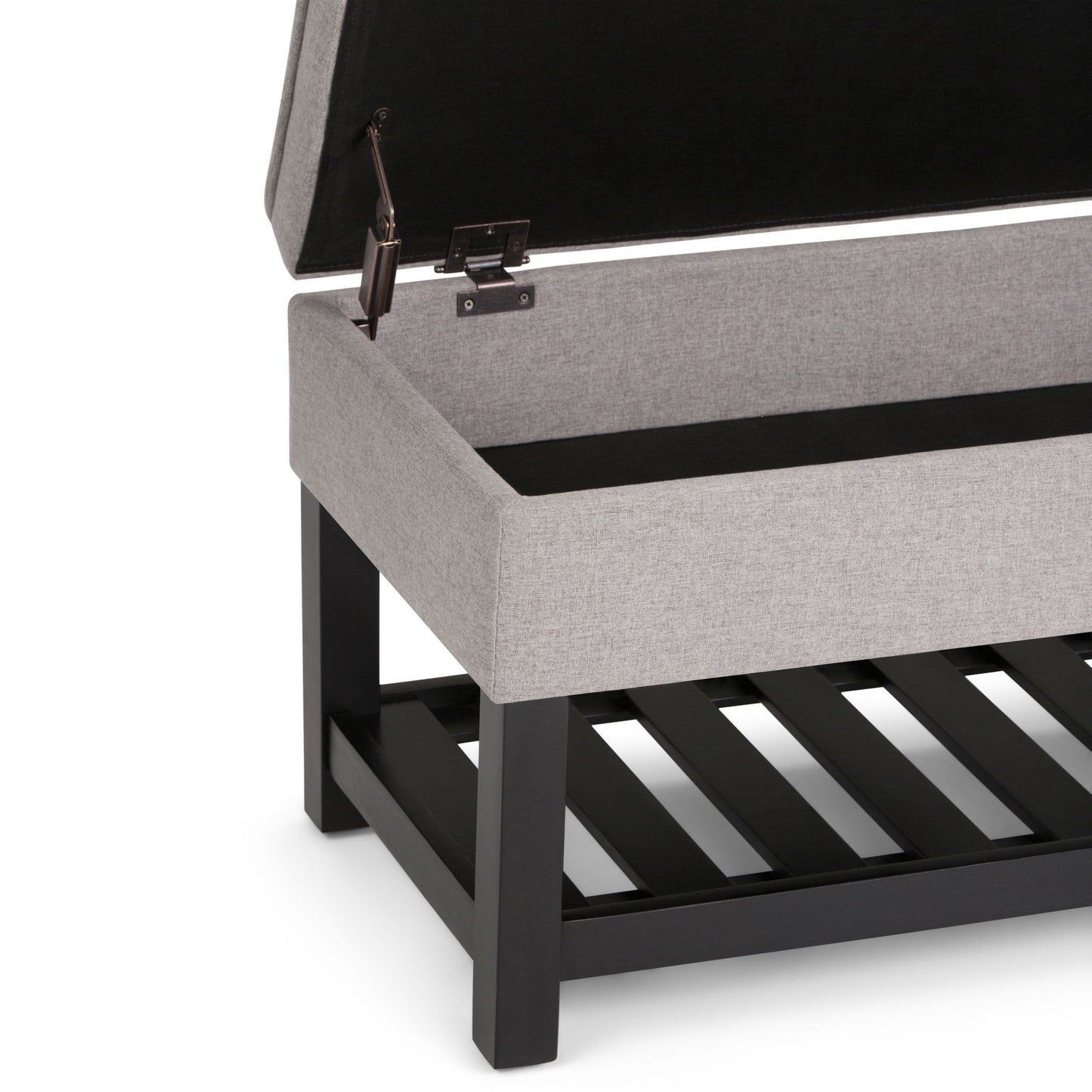 A close-up of the Cosmopolitan Storage Ottoman Bench With Open Bottom in gray upholstery, shown with its lid open to reveal an empty storage compartment and a black wooden slatted lower shelf.