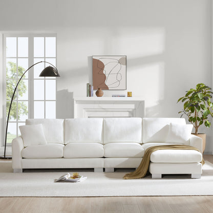 A bright living room with a Modern Oversized Sectional Sofa, two free pillows, a tan throw blanket, black floor lamp, potted plant, white fireplace, abstract wall art, and large windows letting in natural light.
