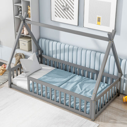 A Tent-Shaped Floor Bed with guardrails and slats sits in a light blue bedroom. The teepee bed features a white mattress, light bedding, and two pillows, while shelves and framed art decorate the walls.
