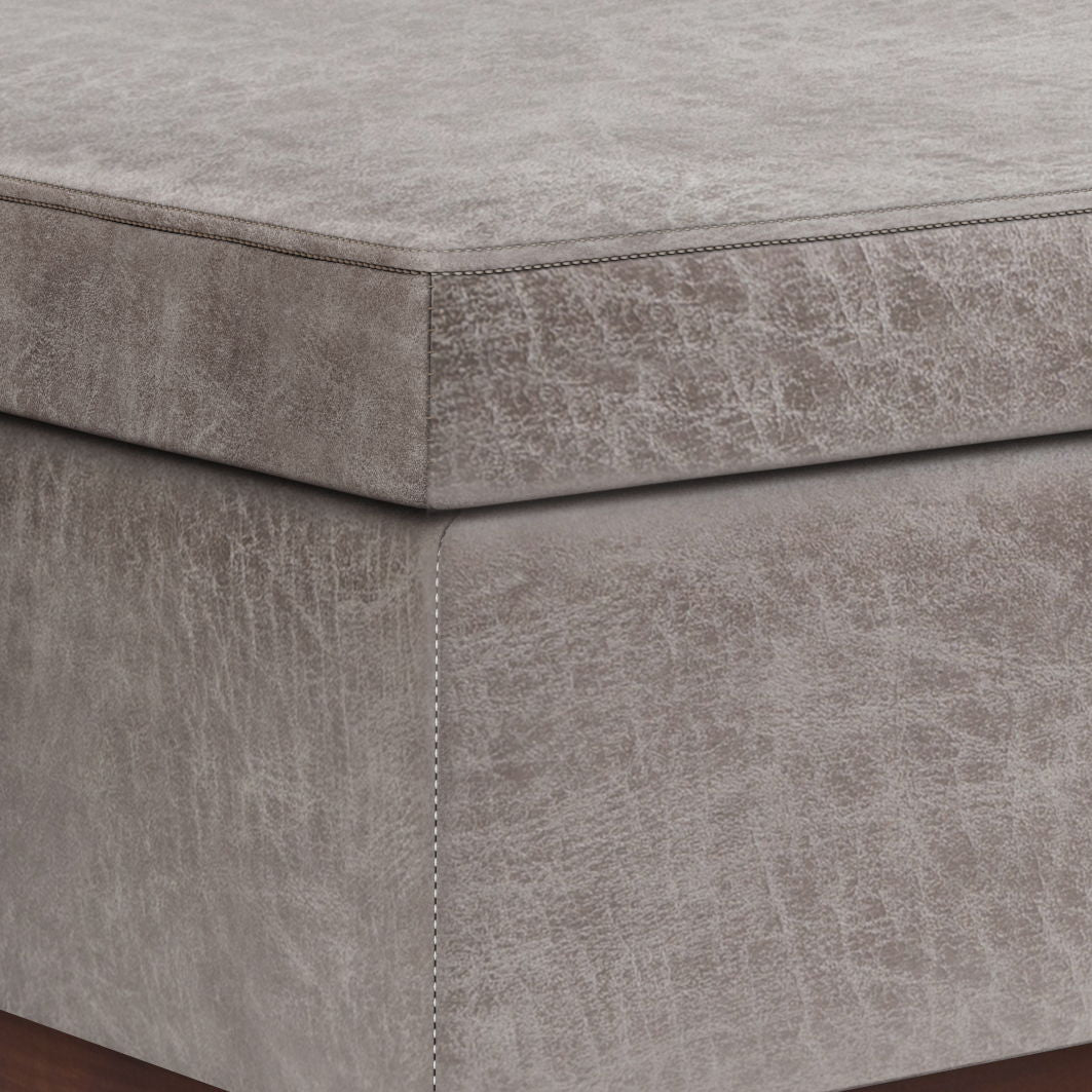 Close-up of the corner of the Owen - Lift Top Large Coffee Table Storage Ottoman, Mid Century Style, featuring gray upholstery with visible stitching and a textured, slightly distressed fabric finish.