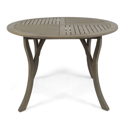 The Hermosa Outdoor Acacia Wood Table features a circular slatted top and four curved legs, displayed against a white background.