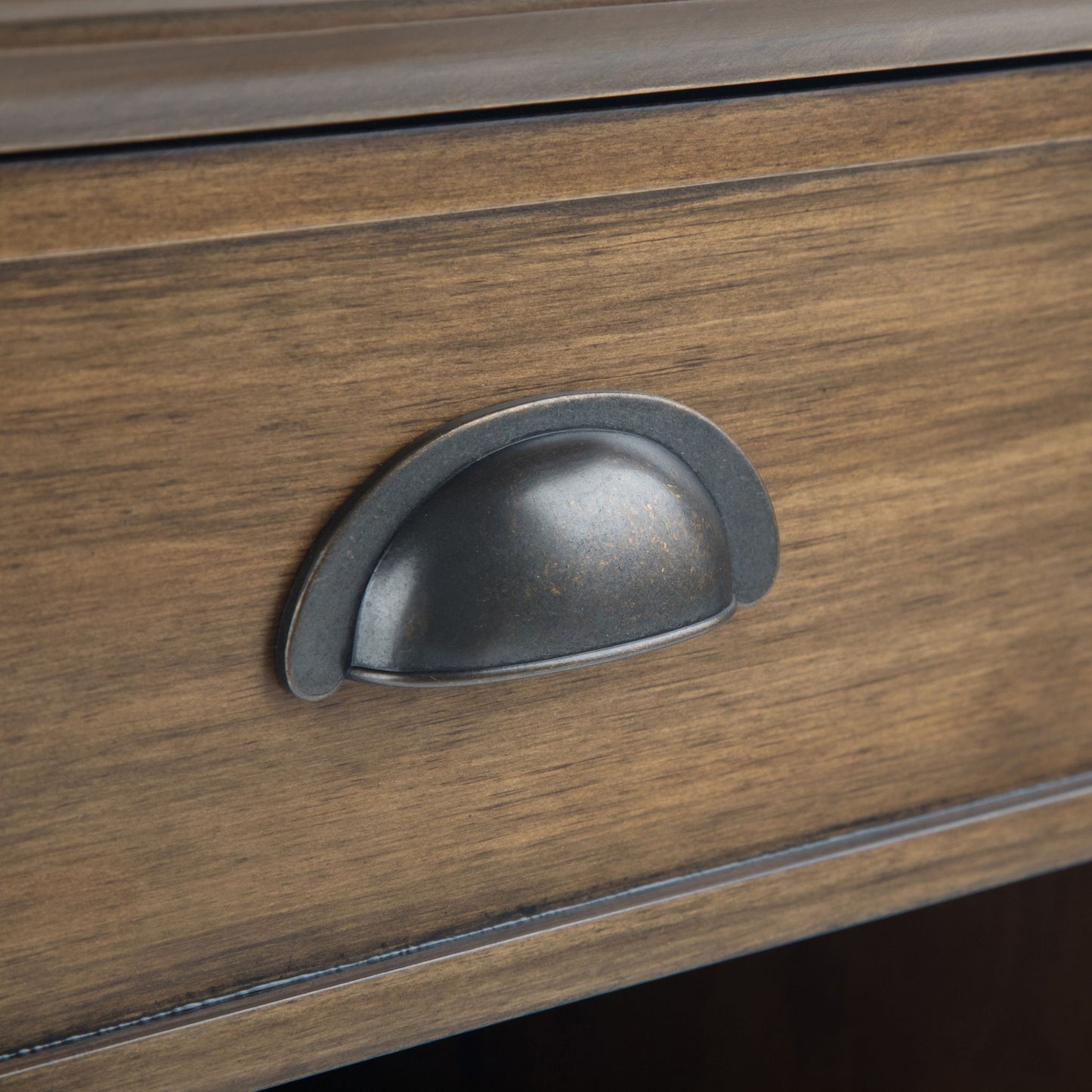 A close-up of the Acadian - Bedside Table, Handcrafted, featuring a wooden drawer with a dark metal cup pull handle at the center and a natural brown finish that highlights the wood grain.