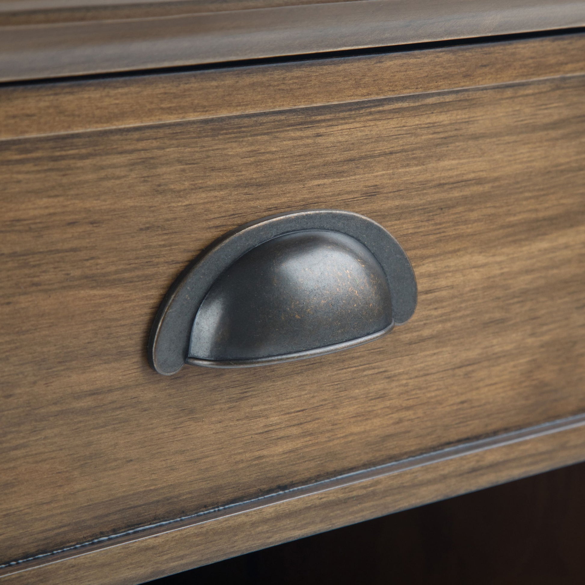 A close-up of the Acadian - Bedside Table, Handcrafted, featuring a wooden drawer with a dark metal cup pull handle at the center and a natural brown finish that highlights the wood grain.