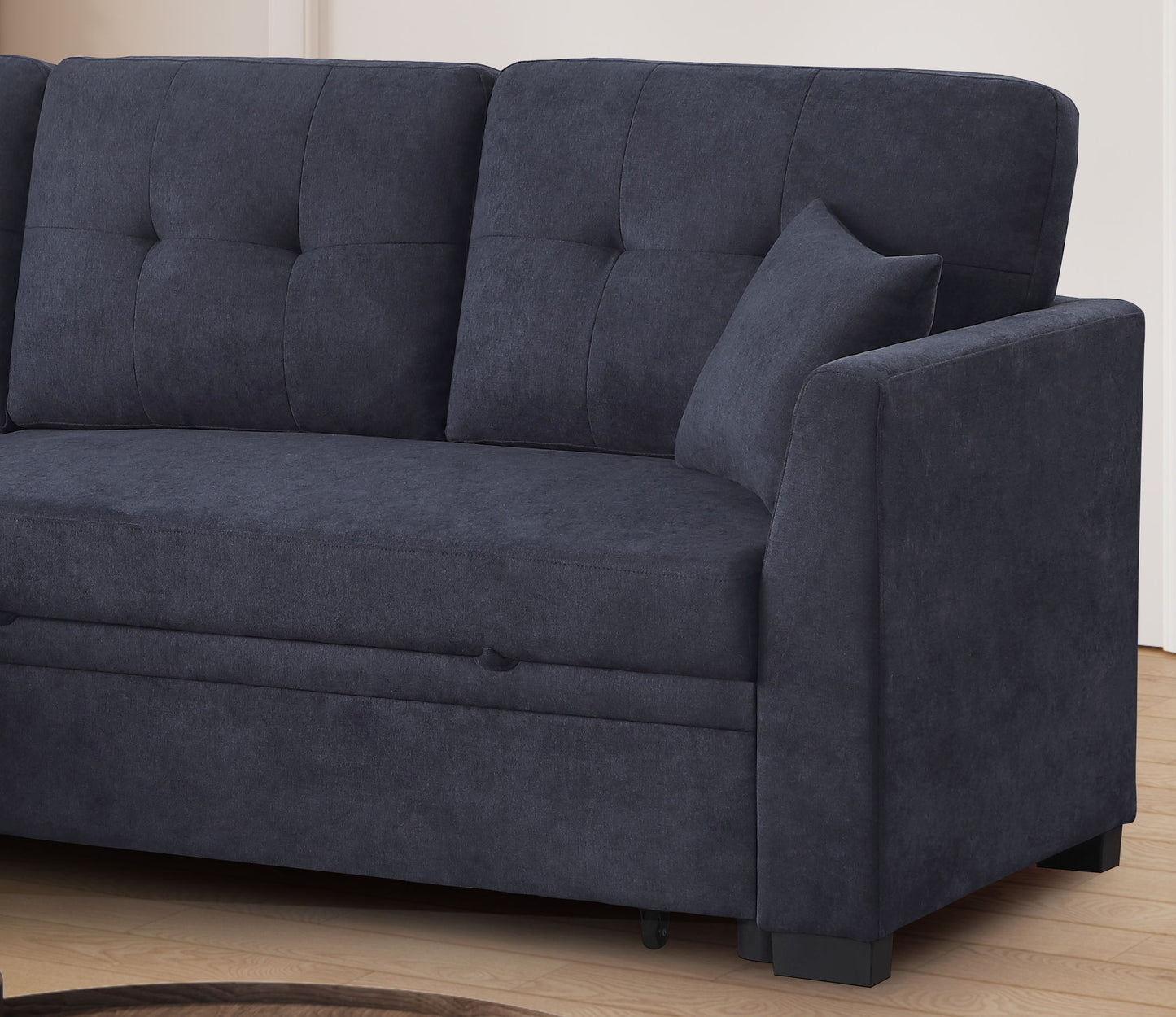 The Sectional Sofa Bed in dark blue features tufted back cushions, a matching pillow, and modern lines. It sits on a light wood floor against a neutral wall, offering stylish comfort and versatility to your living space.