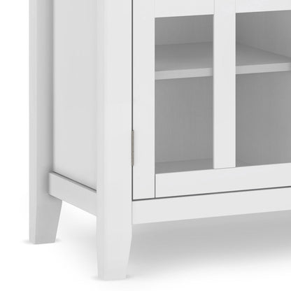 Close-up of the bottom corner of the Artisan - Handcrafted, Tall TV Media Stand in white, featuring a glass door and an interior shelf visible through the glass.
