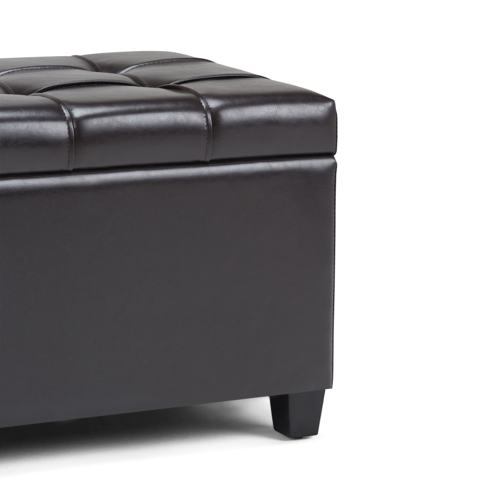 Close-up of the Sienna Upholstered Storage Ottoman Bench in dark brown faux leather with tufted detailing and short black legs, shown on a white background.