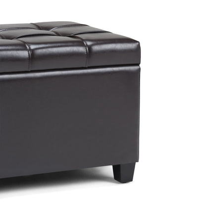 Close-up of the Sienna Upholstered Storage Ottoman Bench in dark brown faux leather with tufted detailing and short black legs, shown on a white background.