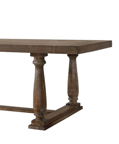 The Bernard - 7 Pieces Dining Room Set features a wooden rectangular table with a thick, rustic brown top and two ornate turned pedestal legs joined by a horizontal base.
