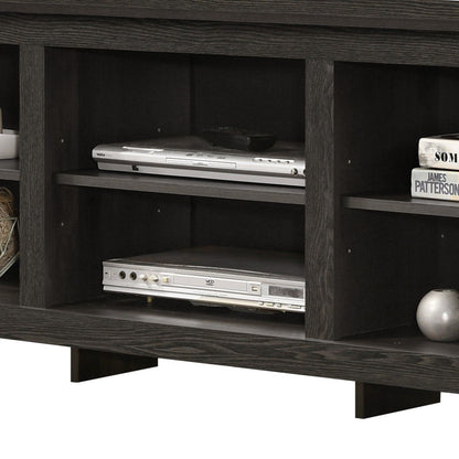 A close-up of the Benito TV Stand with open shelves, displaying two silver players, books, a white round vase, and woven baskets. Cable management is built in for a tidy setup.