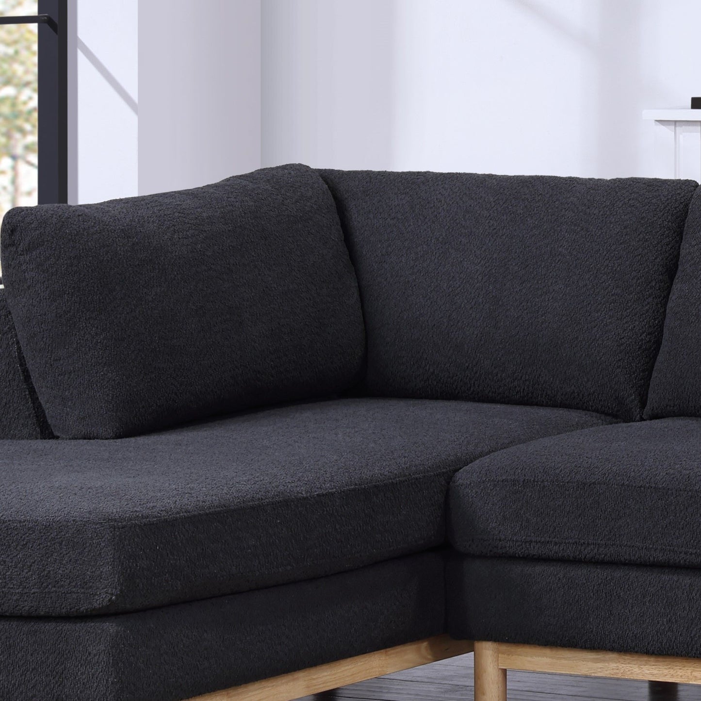 A close-up of the Hallie Wide Sherpa Double Chaise U-Shape Sectional Sofa with wooden legs, shown in a bright room with light walls and a window in the background.