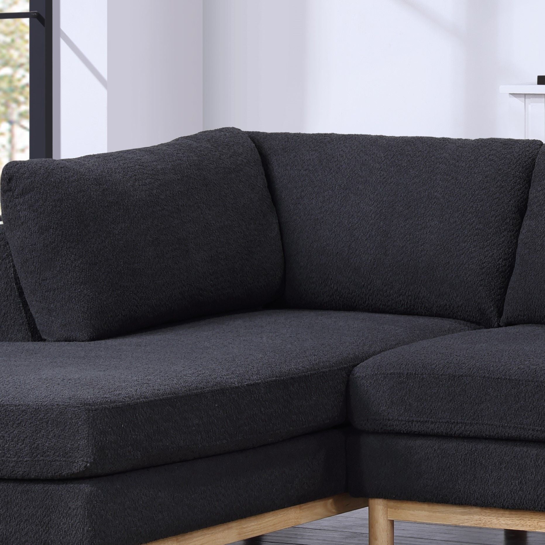 A close-up of the Hallie Wide Sherpa Double Chaise U-Shape Sectional Sofa with wooden legs, shown in a bright room with light walls and a window in the background.