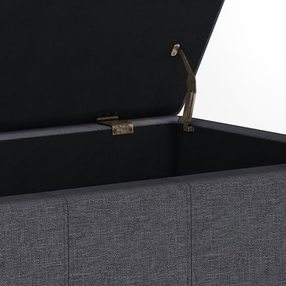 A close-up of the Dover - Upholstered Storage Ottoman Bench, featuring an open gray fabric exterior, hinged lid with metal support, and an empty interior lined with dark fabric.
