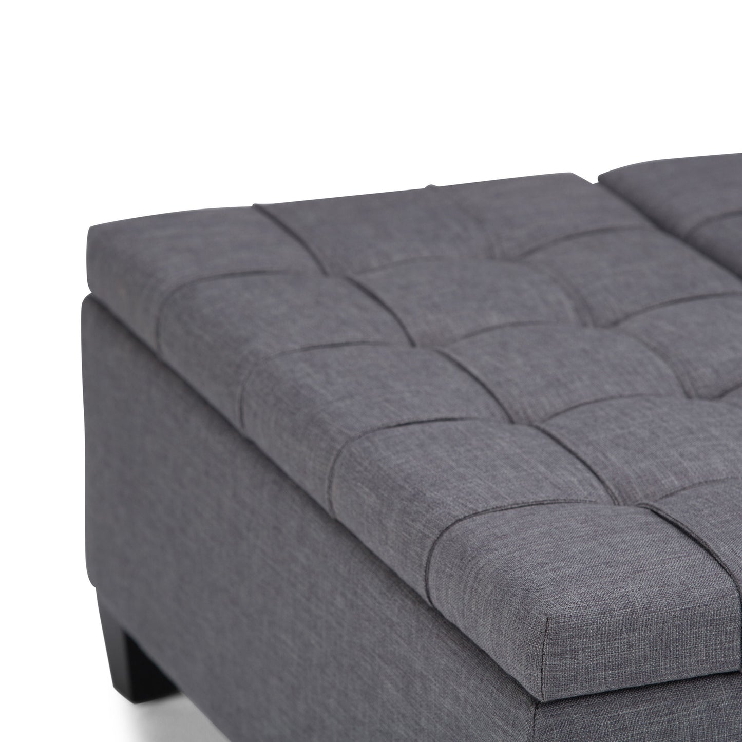 Close-up of the Harrison Upholstered Coffee Table Storage Ottoman, featuring a modern rectangular design, gray fabric with tufted cushioning, visible stitching, short black legs, and a smooth contemporary finish.