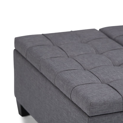 Close-up of the Harrison Upholstered Coffee Table Storage Ottoman, featuring a modern rectangular design, gray fabric with tufted cushioning, visible stitching, short black legs, and a smooth contemporary finish.