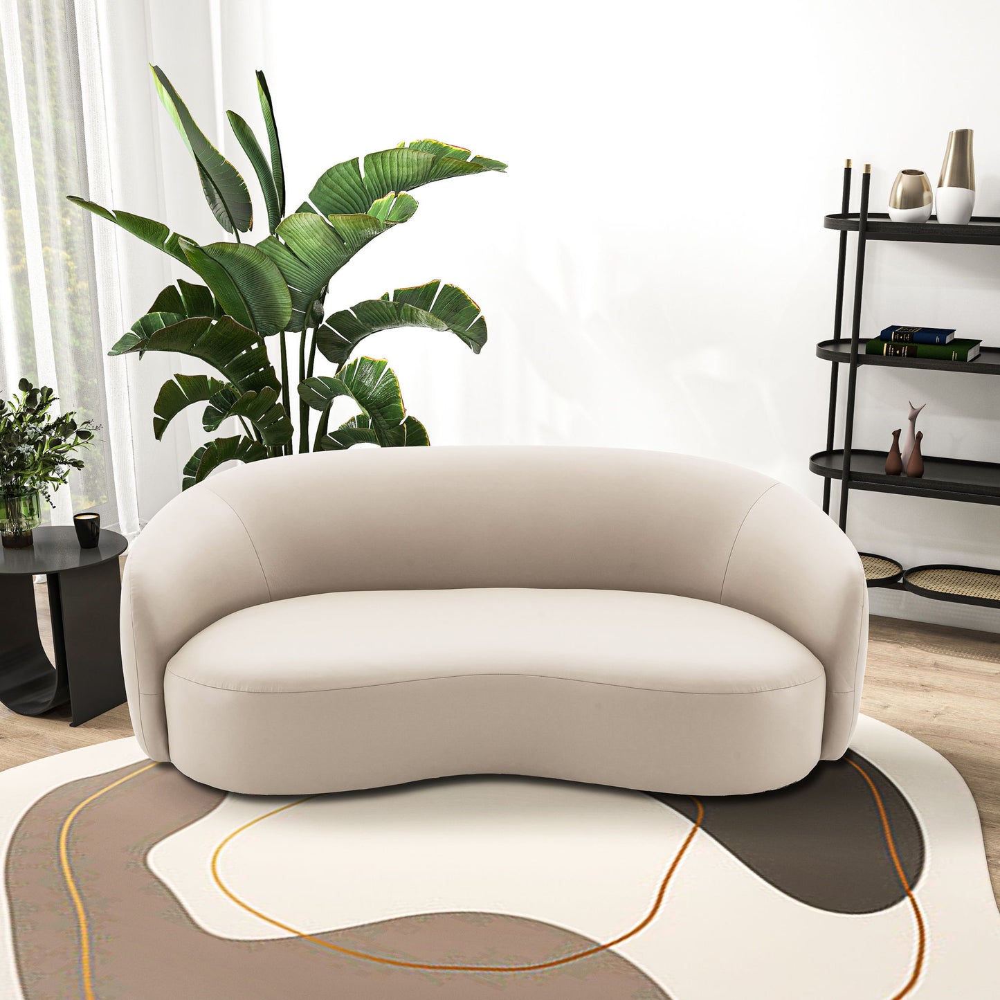 A modern living room featuring the Porter - Comfortable Sofa in beige on an abstract-patterned rug, complemented by a large green plant, black side table with plants, and a black shelving unit with decor against a white wall.