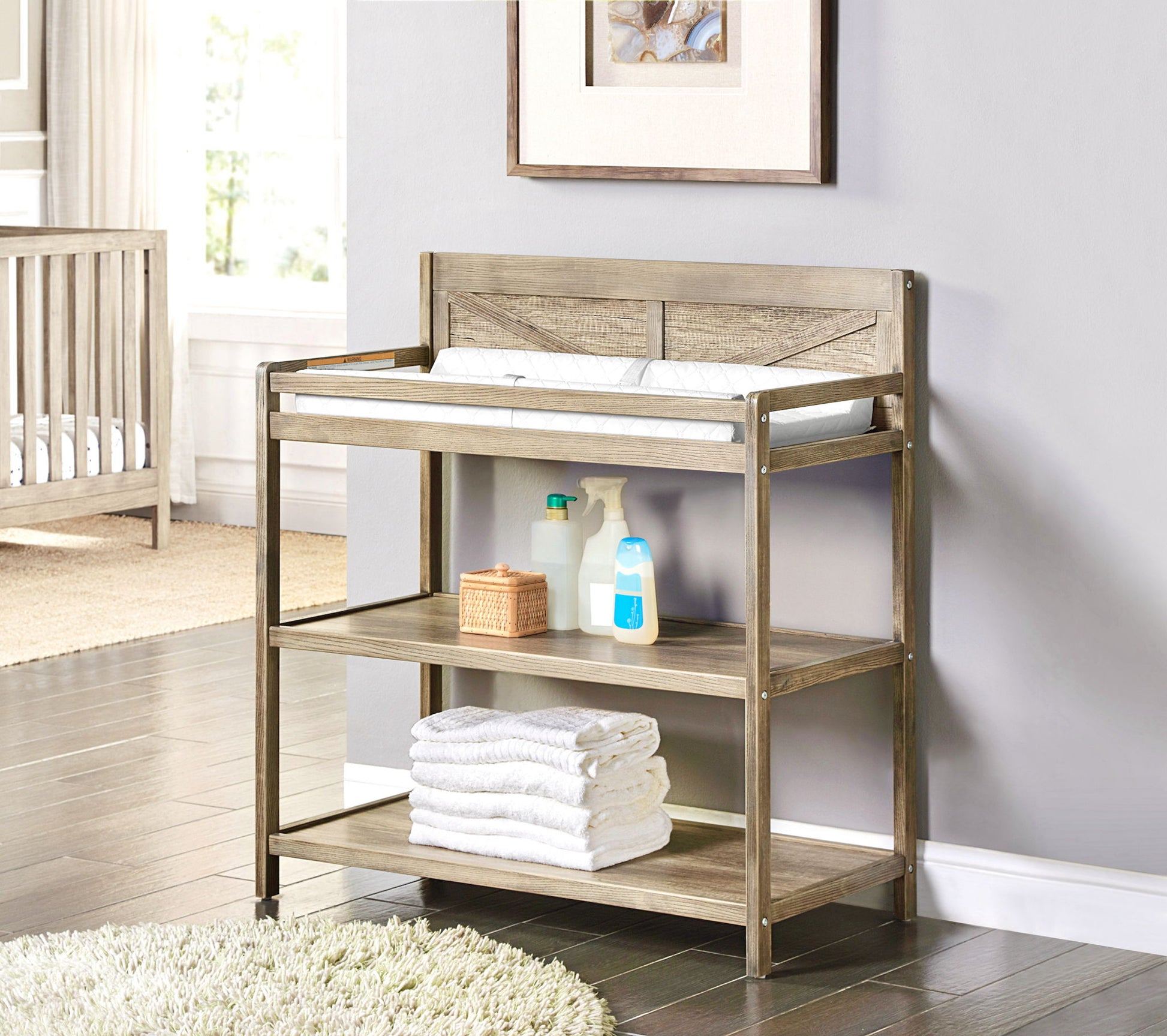 The Barnside - Changing Table Vintage features a padded changing mat, shelves with towels, wipes, bottles, and baby care items, all set in a sunlit nursery room.