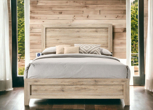 The Miquell Panel Bed, dressed in neutral bedding and decorative pillows, stands against a light wood-paneled wall between tall windows with sheer white curtains and views of lush greenery outside.