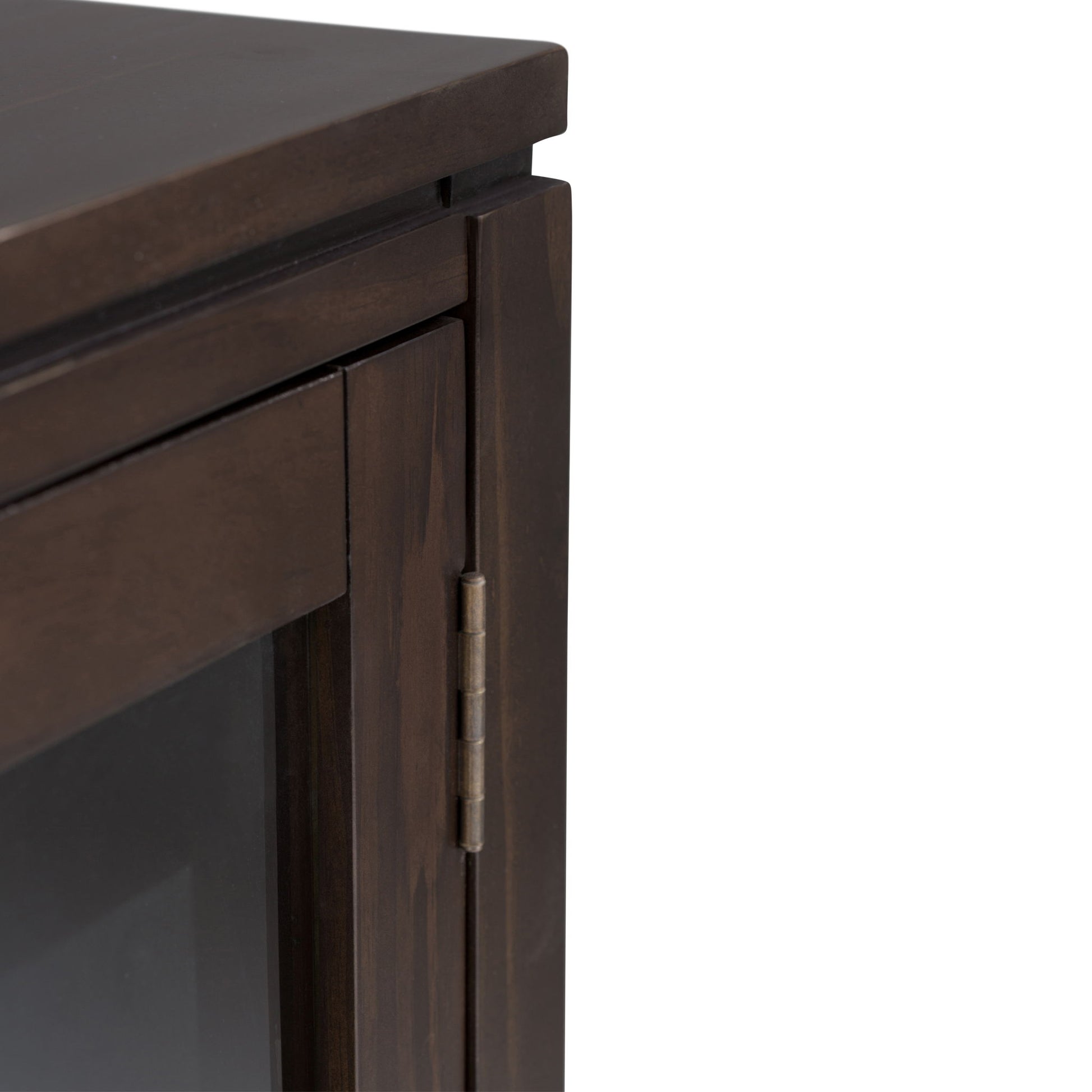 Close-up of the top corner of the Cosmopolitan - Handcrafted Medium Storage Cabinet, highlighting the dark wood edge, hinge, and part of its glass door panel.