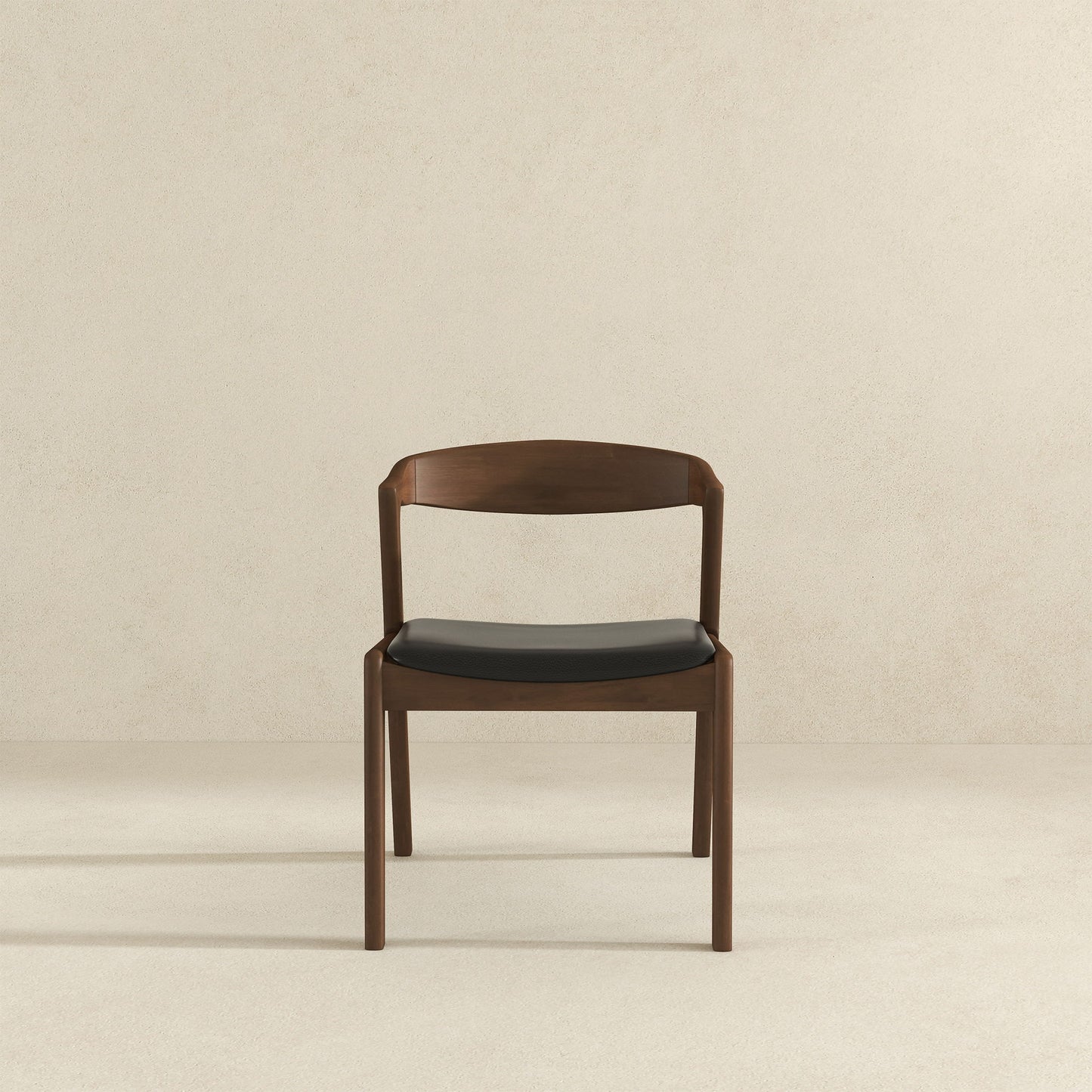 The Dakota Mid-Century Modern Velvet Dining Chair (Set of 2) features a sleek, minimalist design with a curved backrest and black velvet seat, shown against a plain light beige wall and floor.