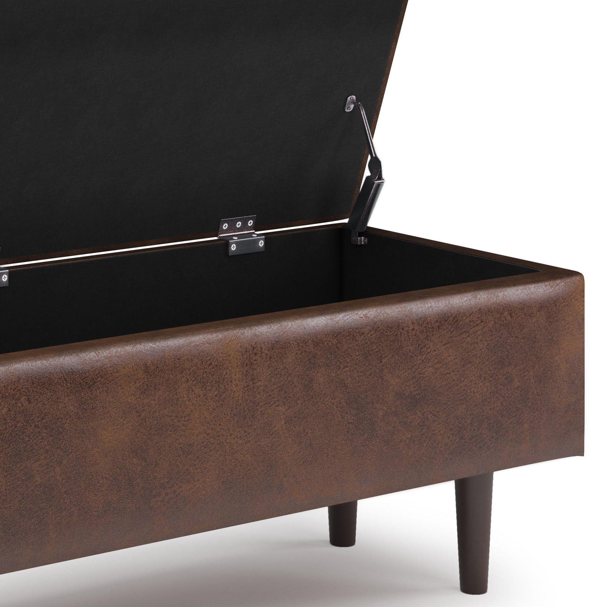A close-up of the Shay Large Square Coffee Table Storage Ottoman in brown faux leather, shown with its lid open to reveal a spacious black-lined interior and short wooden legs in mid-century style.