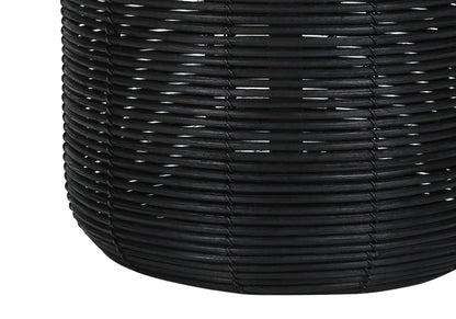 Close-up of a modern table lamp crafted from black rattan, highlighting the detailed interlaced texture and cylindrical shape with gently curved sides.